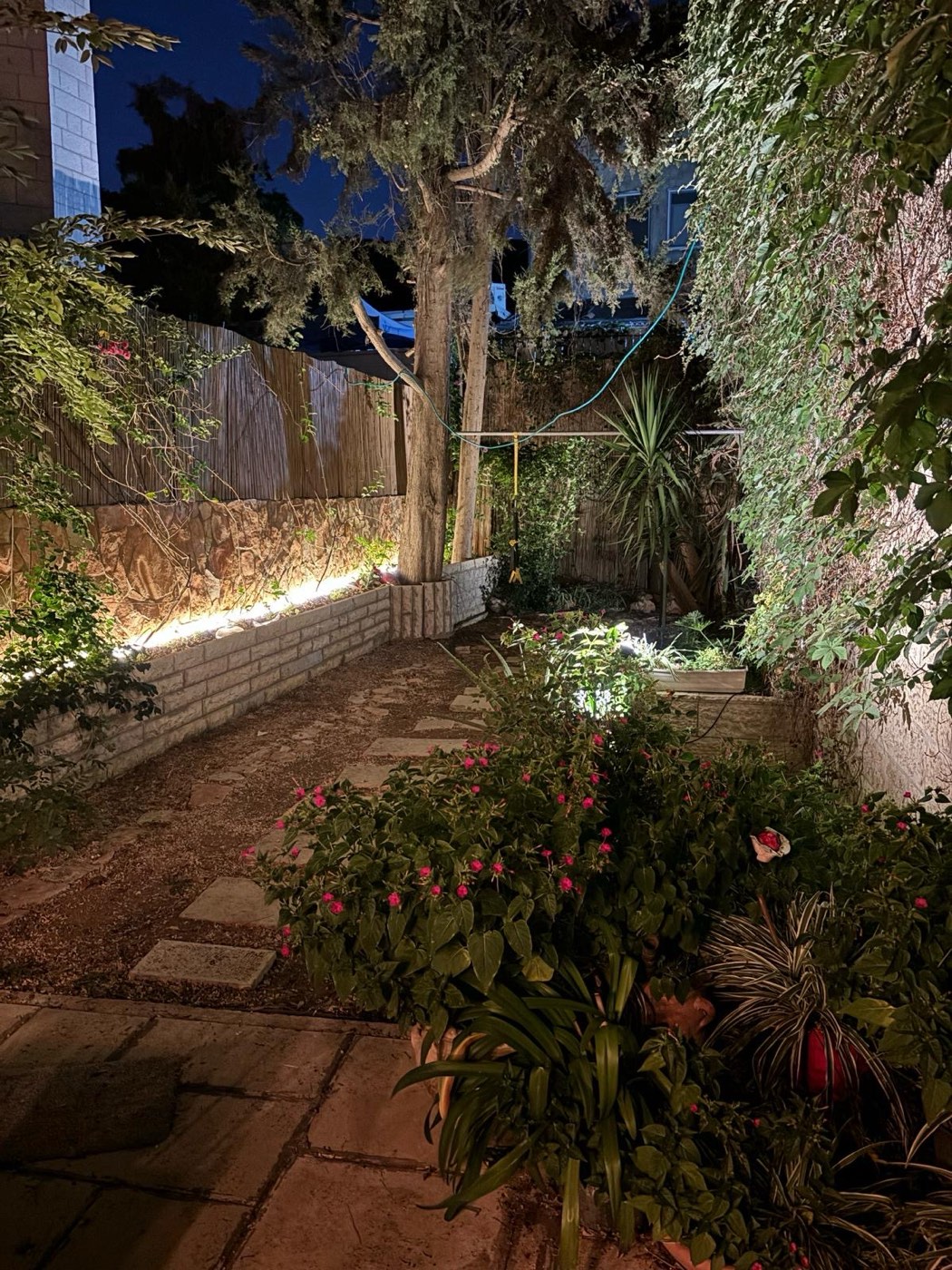 תאורת שביל וקיר עם גוונים חמים בגינה פרטית